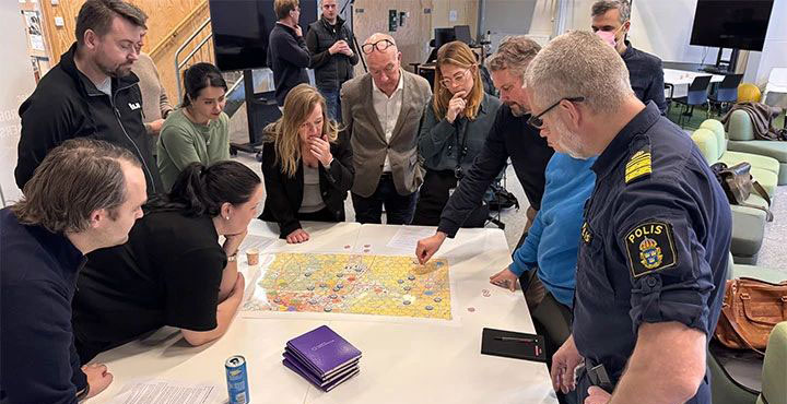 Människor diskuterar scenarier kring ett bord.