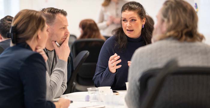 Kursdeltagare i samtal runt bord.