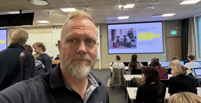 Jonas Landgren framför en grupp studenter i en sal.