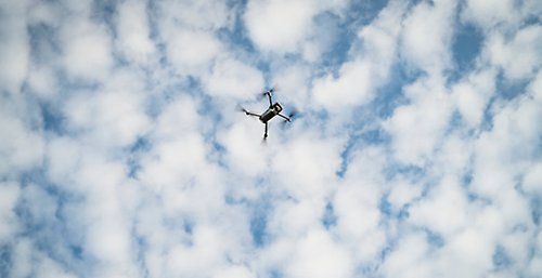 Flygande drönare mot molnig himmel.
