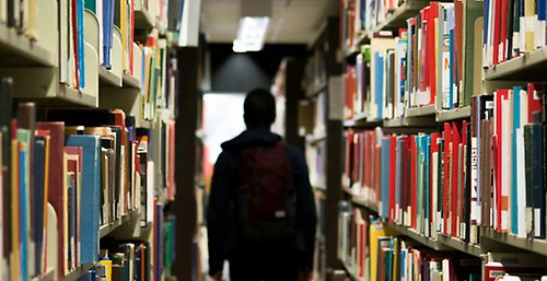 Person mellan hyllrader på bibliotek